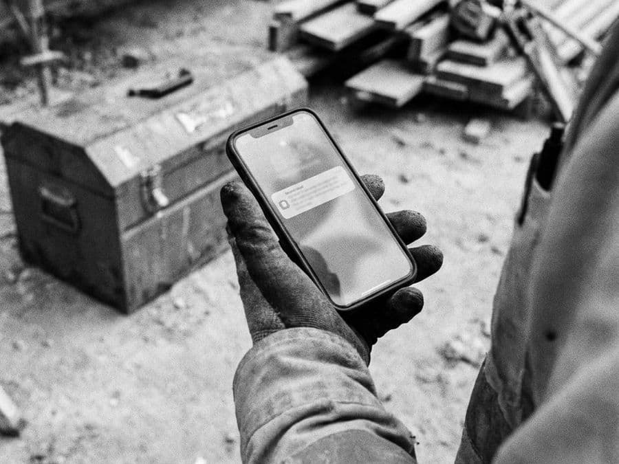 A hand holding a phone on a job site.